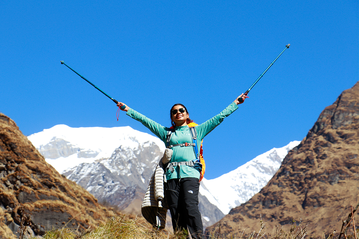 female trekker raising hiking sticks on air